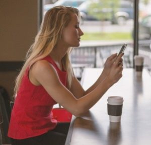 girl using a phone while having a coffee